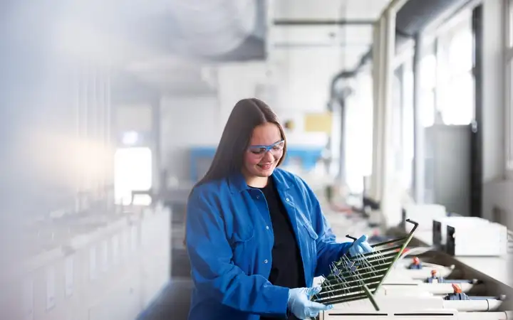 A SCHOTT employee examines small hermetic components on a rack. 