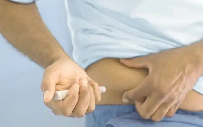Man injecting himself in the stomach with medication using an autoinjector