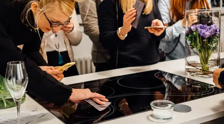 Visitors at a SCHOTT CERAN® event, photographing and testing a glass-ceramic cooktop