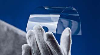An ultra-thin glass bends in a scientist’s hand