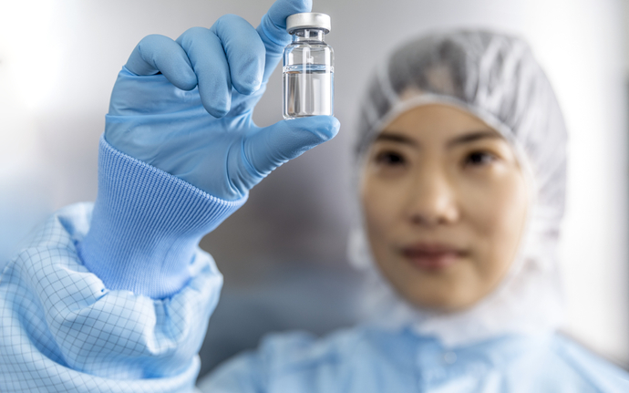 Person in cleanroom clothing testing an ampoule.