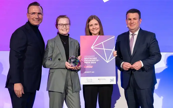 Zwei Männer und zwei Frauen in Businesskleidung präsentieren Stolz den gewonnen Deutschen Fachkräftepreis.