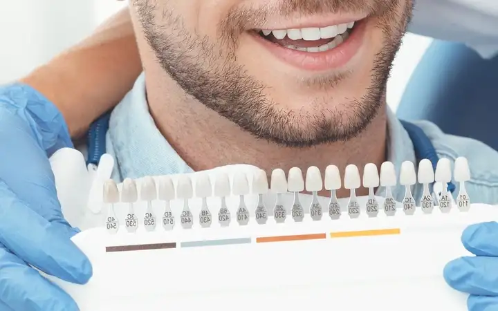 Man being shown a range of prosthetic teeth in a dental surgery