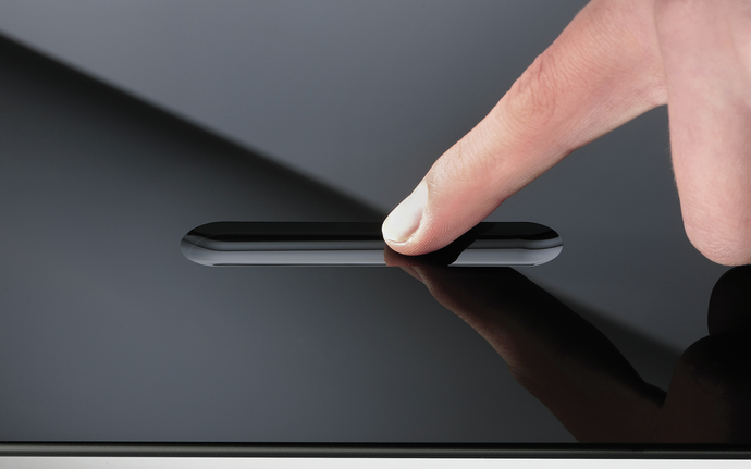 Finger touching a groove in a glass processed with SCHOTT® Smart Touch technology
