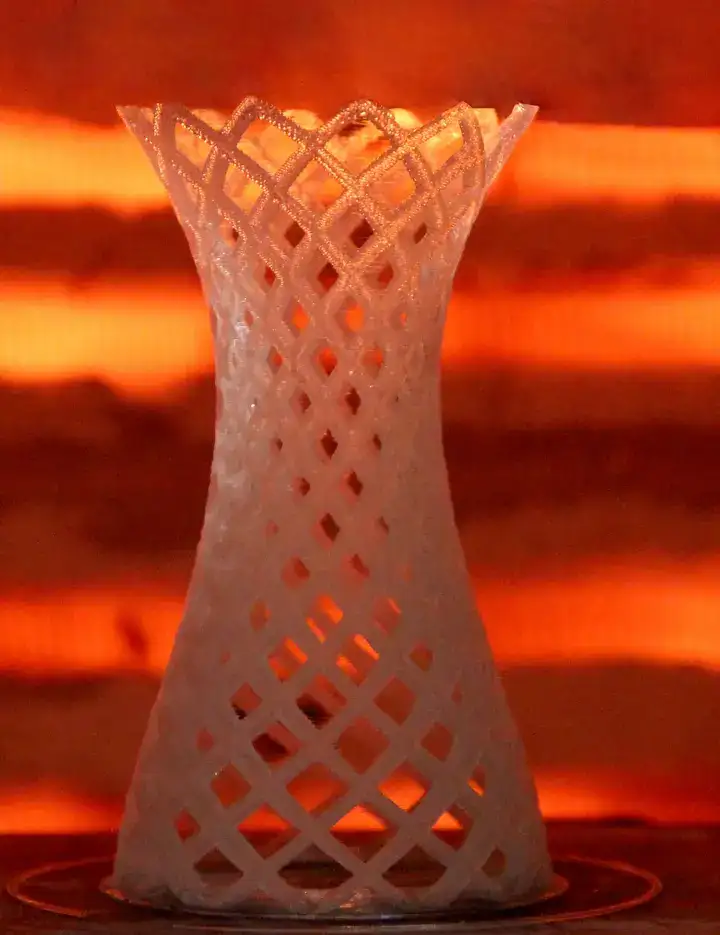 3D printed glass ornament in front of orange furnace