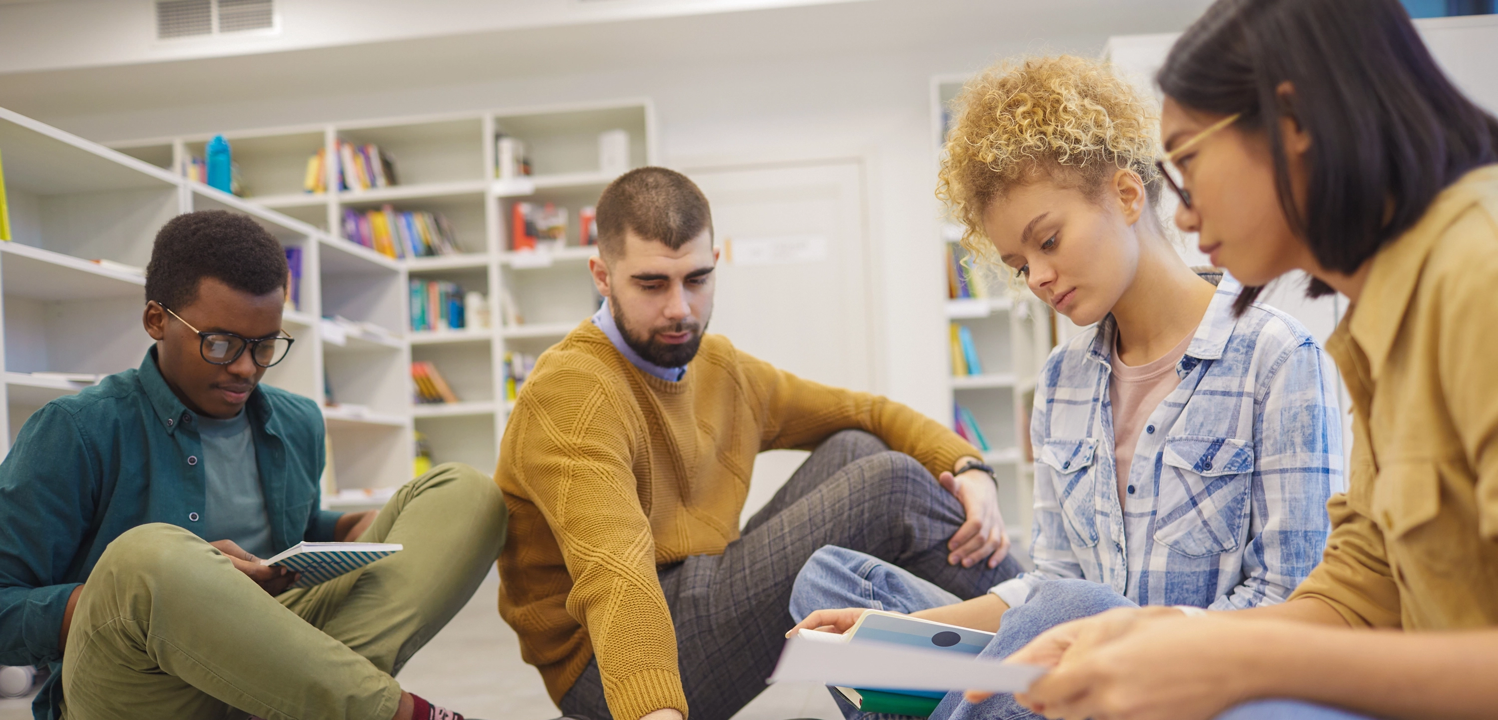 Vier Studierende sitzen auf dem Boden und arbeiten