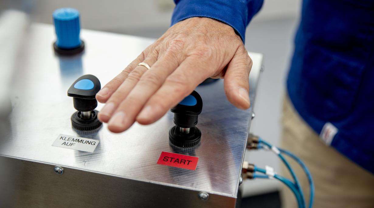 Hand pushes the start button of a drop tester