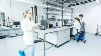 Female technician walks across a laboratory with colleagues in background