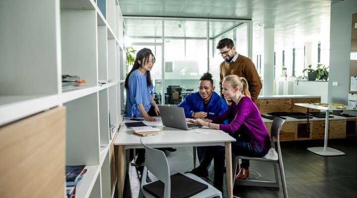 Two women and two men looking at a laptop