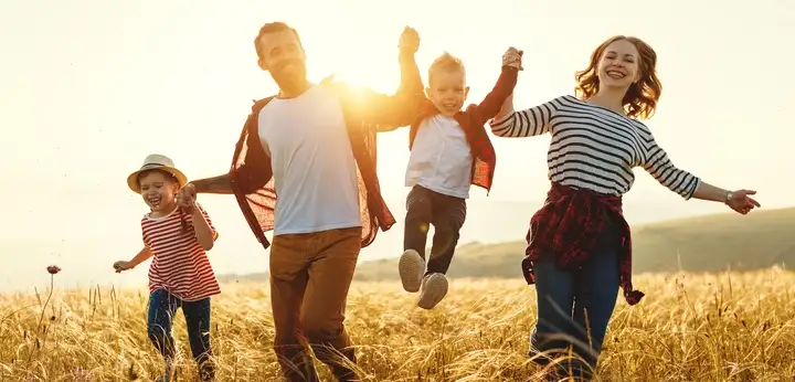 Family running through a wheat field at sunset