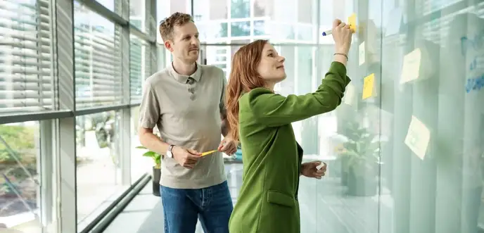 Frau und Mann stehen am Whiteboard