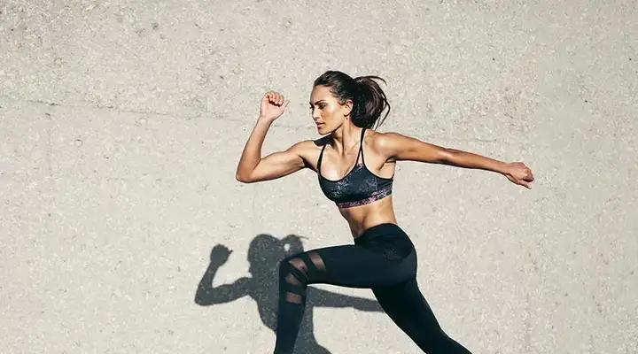 Female in sportswear running alongside a wall