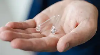 Tiny customized glass containers sitting in the palm of a hand