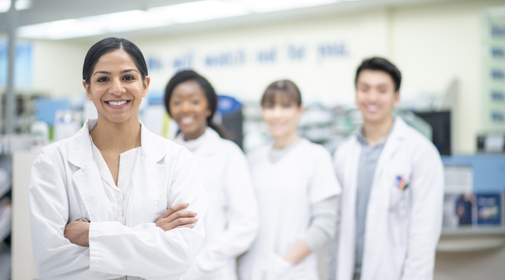 Smiling female scientist with colleagues in a laboratory.