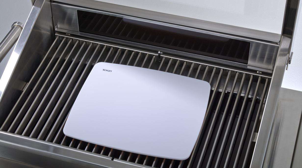 Silver grill with open lid and white glass-ceramic sample