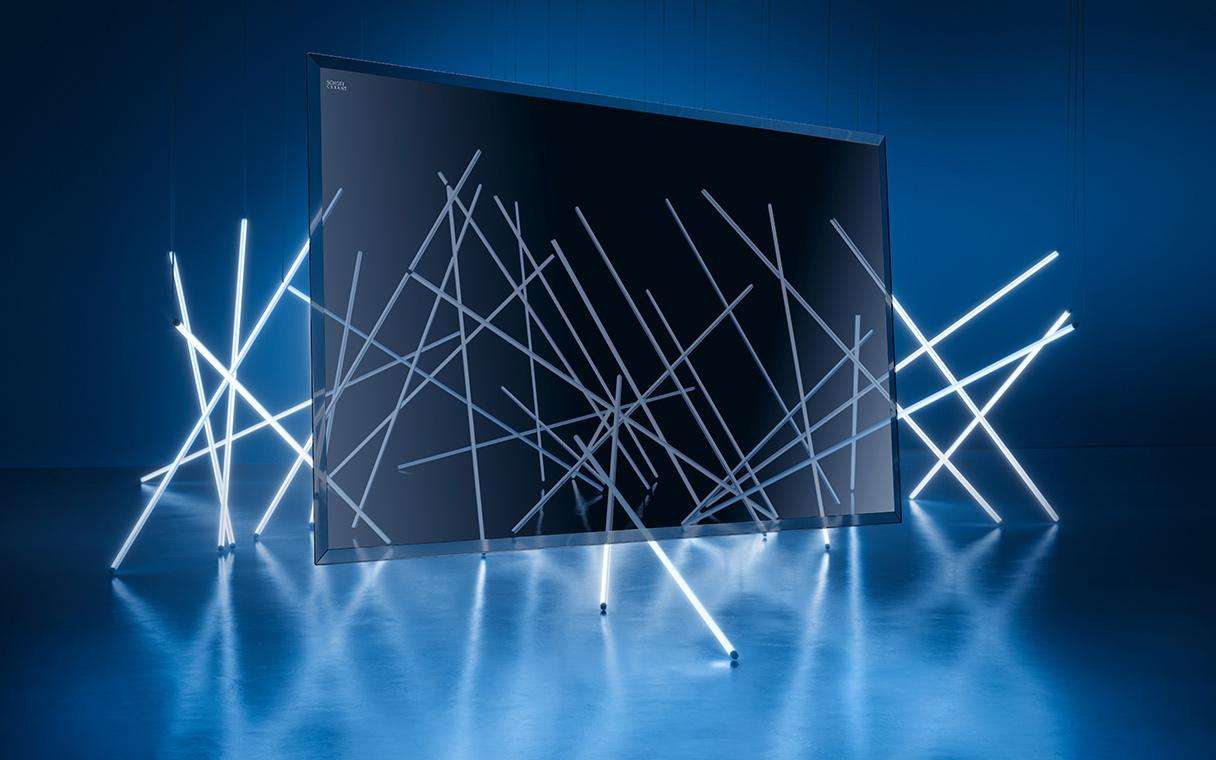 SCHOTT CERAN Luminoir™ Glaskeramik schwebt im Raum vor einer Installation aus Lichtstäben, die hindurchscheinen.