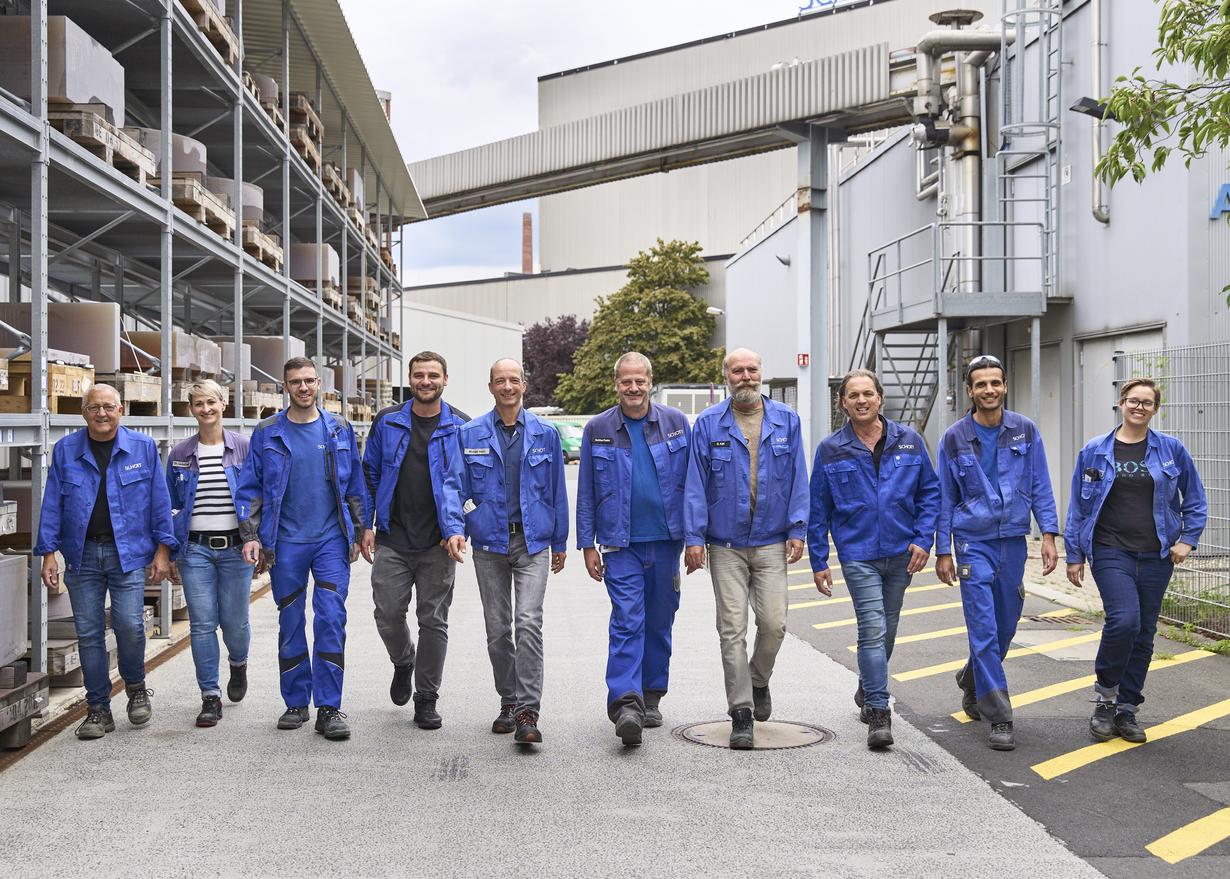 	Michael Hahn and his colleagues walking side by side in their blue work gear on the SCHOTT premises in Mainz