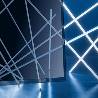 Ecke einer SCHOTT CERAN Luminoir™ Glaskeramik vor einer Installation aus Lichtstäben, die hindurchscheinen.