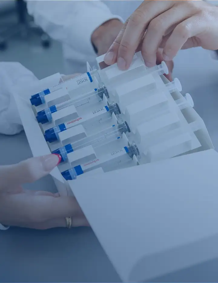 Two SCHOTT employees examine a box of SCHOTT TOPPAC® infuse polymer syringes