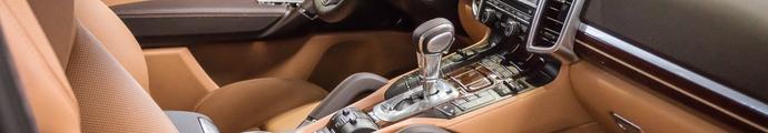 Brown interior of a luxury vehicle with dashboard, steering column and gear stick