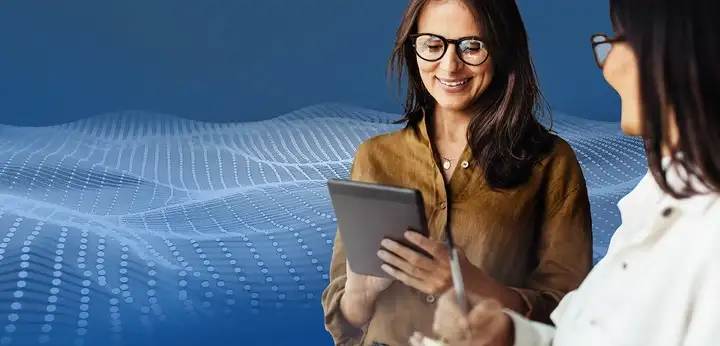 Two female pharmaceutical experts discussing while looking at a tablet