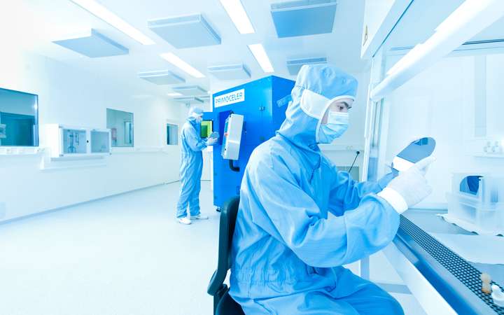 Two scientists working in a laboratory looking at mirror discs