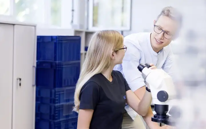 SCHOTT employees collaborate around a microscope.