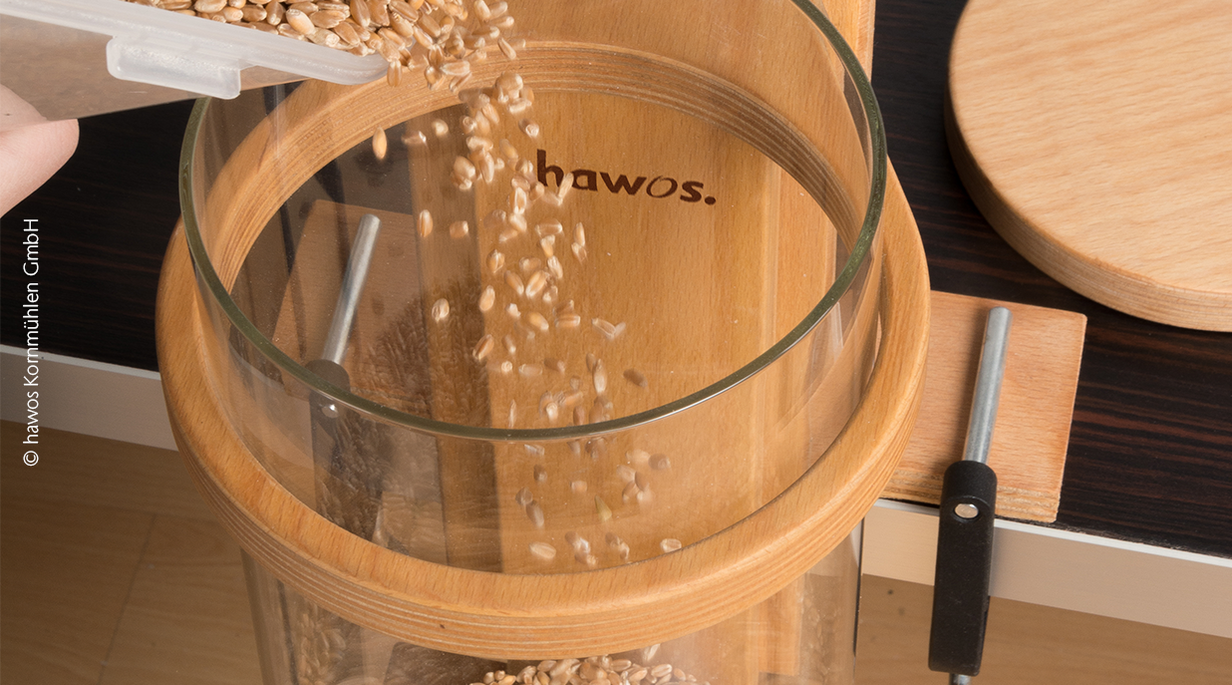 Grains being poured into a large glass circular container