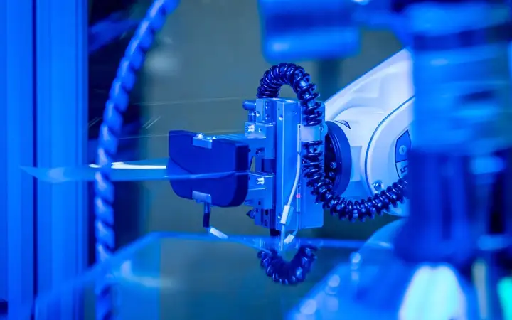 Close-up of a robotic arm with precision tool under blue lighting.