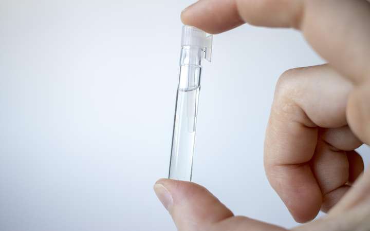 Glass tube containing clear liquid held by fingers