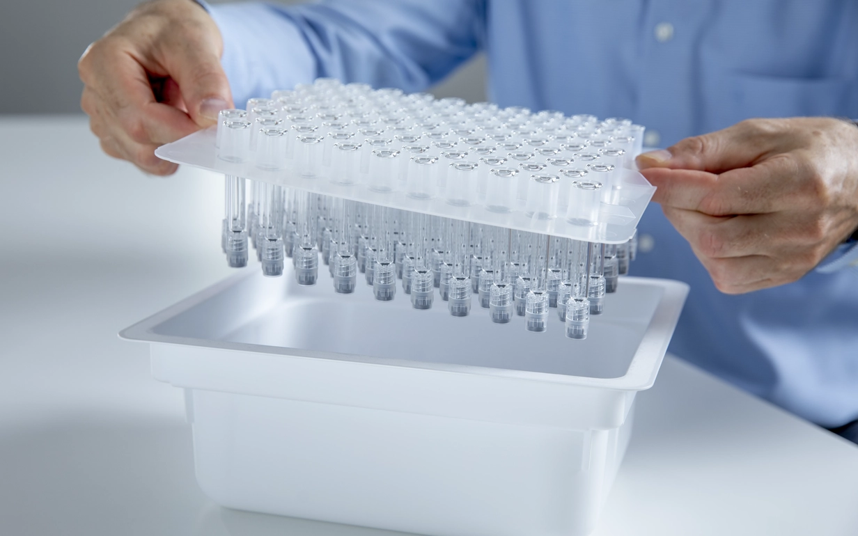 Two hands hold a container with prefillable glass syringes from SCHOTT Pharma.