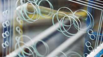 A close-up view of a hob top  glass surface featuring multiple concentric circles and horizontal lines, with a blurred background showing blue and yellow elements.