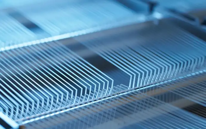 Side angle of large volume of glass substrates in racks with blue lighting reflection.