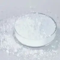 White glass-ceramic powder in a petri dish, with some spilled on a grey surface.