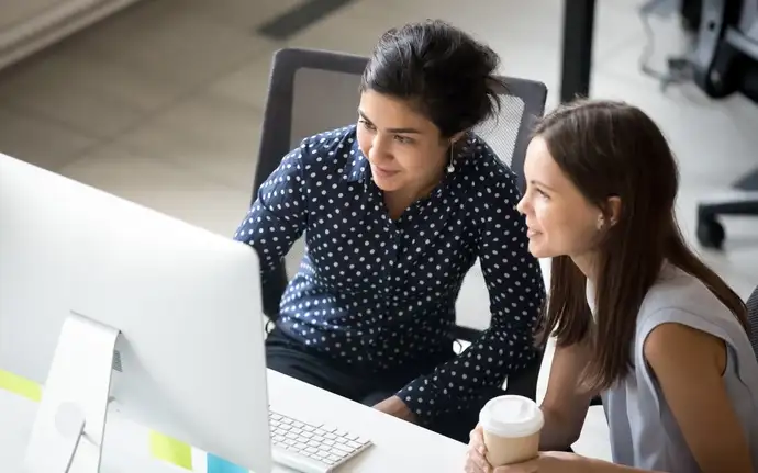 Dois jovens olhando para um monitor em um escritório