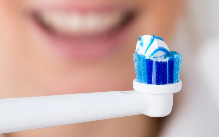 Close up of an electric toothbrush in front of a female mouth