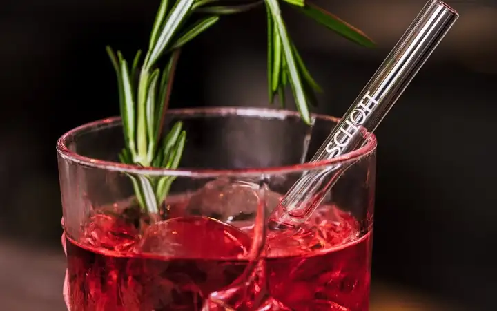 Red drink with ice and a SCHOTT glass straw