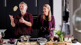 Two people have fun cooking, man throws dough in the air