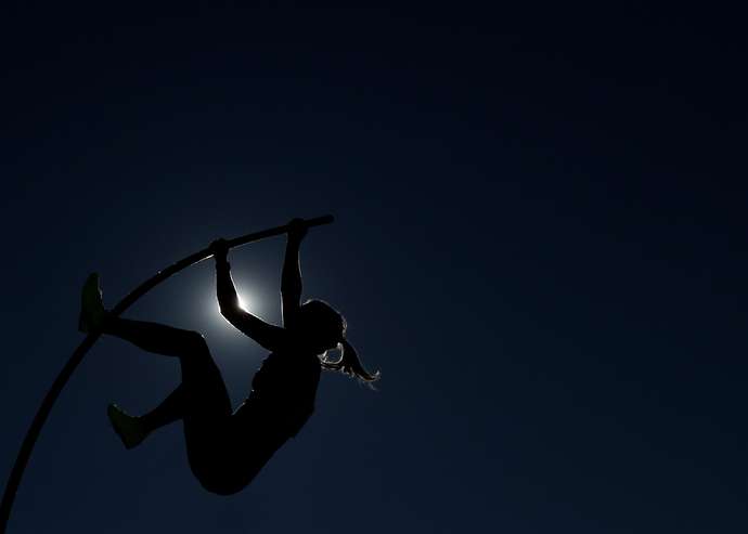 Person doing pole vault at night
