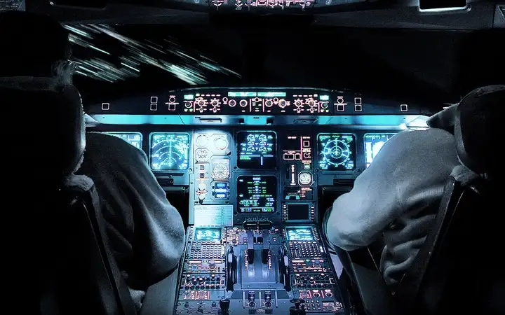 Interior of an aircraft cockpit with controls and displays lit up