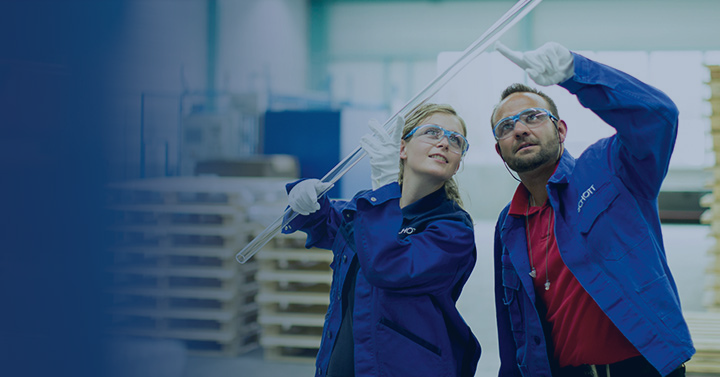 Two employees looking at a glass tubing from SCHOTT