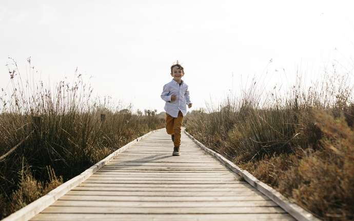 Young boy running down a wooden walkway
