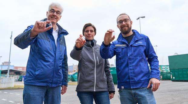 Marco Müller, Anke Reinung and Marius Amschler standing on a concrete square and holding medicine bottles into the camera