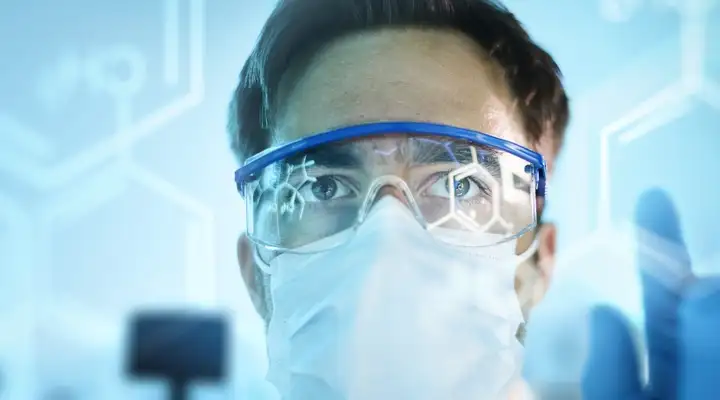 Male doctor in safety glasses looking forwards