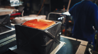 A glowing red molten hot block of glass is ready for processing