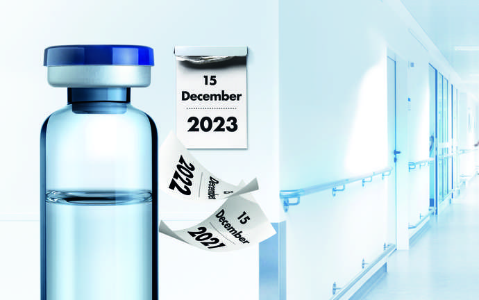 Clear pharmaceutical glass vial made by SCHOTT with calendar in background