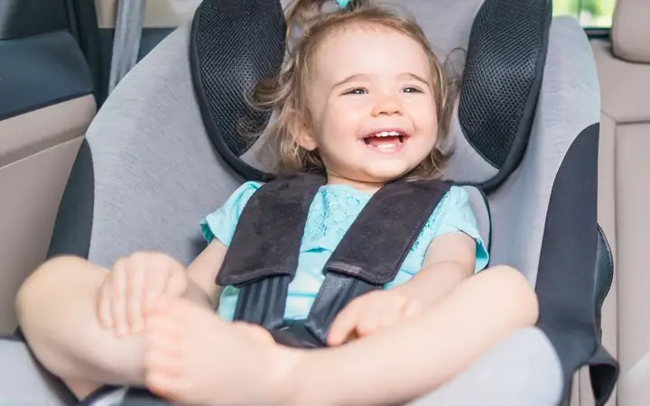 Small baby in a child seat in the back of a luxury vehicle