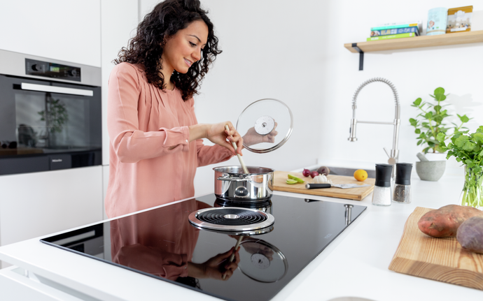 Woman stirring a pan on a SCHOTT CERAN® glass-ceramic cooktop