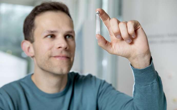 Hombre joven mirando un cartucho de vidrio farmacéutico