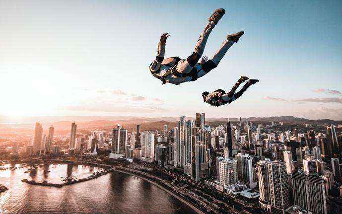 Two skydivers freefall over a city